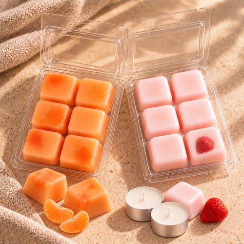 Pack Dúo Frutal de Casa Calma con wax melts de mandarina y fresa y nata, en cubos naranjas y rosas dentro de envases abiertos y 2 velas de te