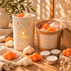 Pack Noche Estrellada de Casa Calma con quemador Luna encendido y wax melts de mandarina y champán en forma de nubes blancas y naranjas.
