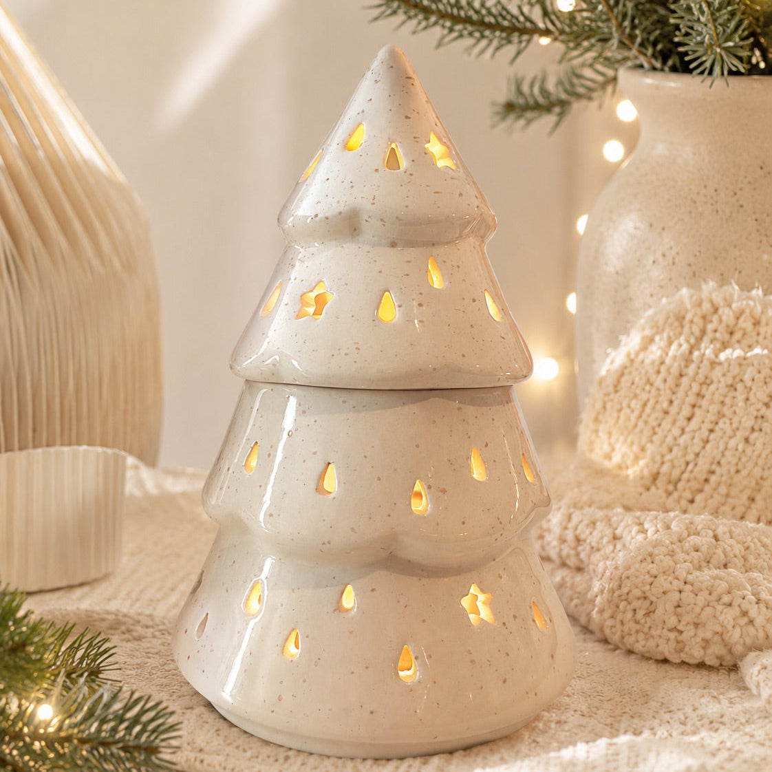 Quemador de wax melts con forma de árbol de Navidad en cerámica blanca, iluminado y decorado con pequeñas estrellas.