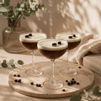 Tres velas Espresso Martini Casa Calma en copas de cóctel sobre bandeja de mármol, rodeadas de granos de café