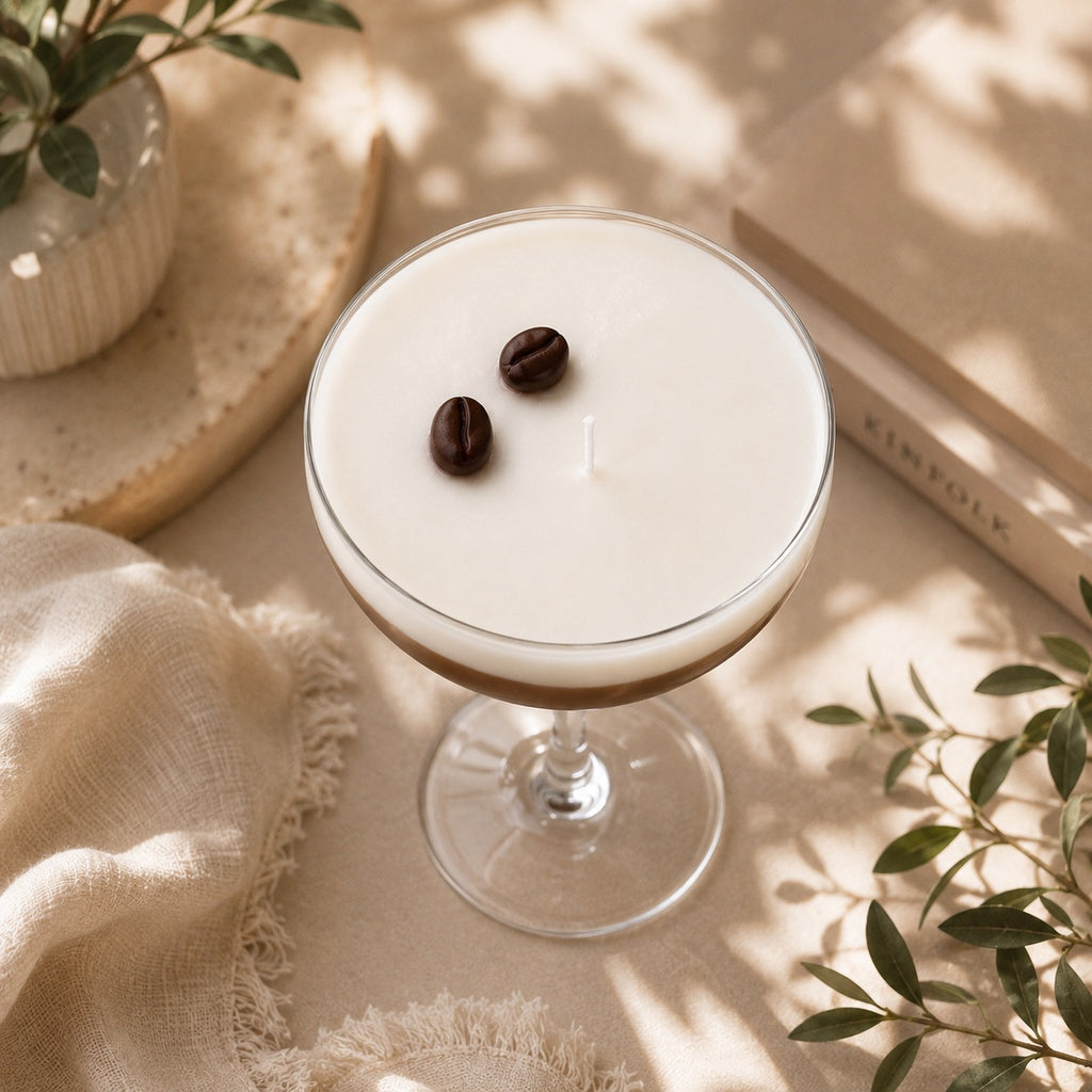 Vista cenital de vela artesanal Espresso Martini Casa Calma en copa de cristal con dos granos de café sobre soja blanca