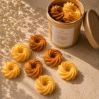 Wax melts de vainilla y coñac de Casa Calma en forma de aros en espiral, en tonos amarillo y caramelo, junto a su envase kraft abierto